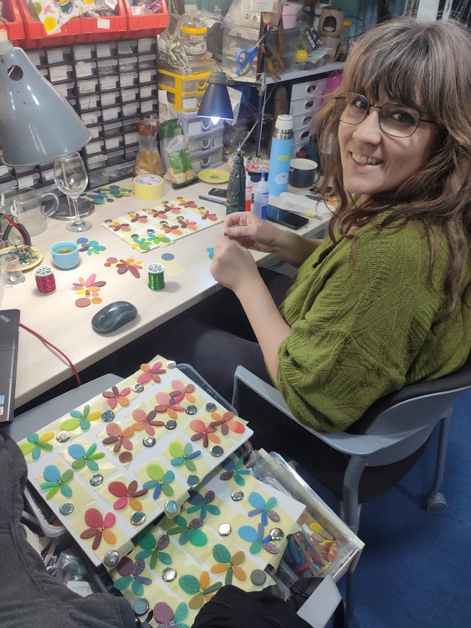 Jasmina working at the atelier table among colourful jewellery elements